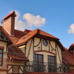 A beautiful European-style house with a distinctive red tiled roof against a clear blue sky.