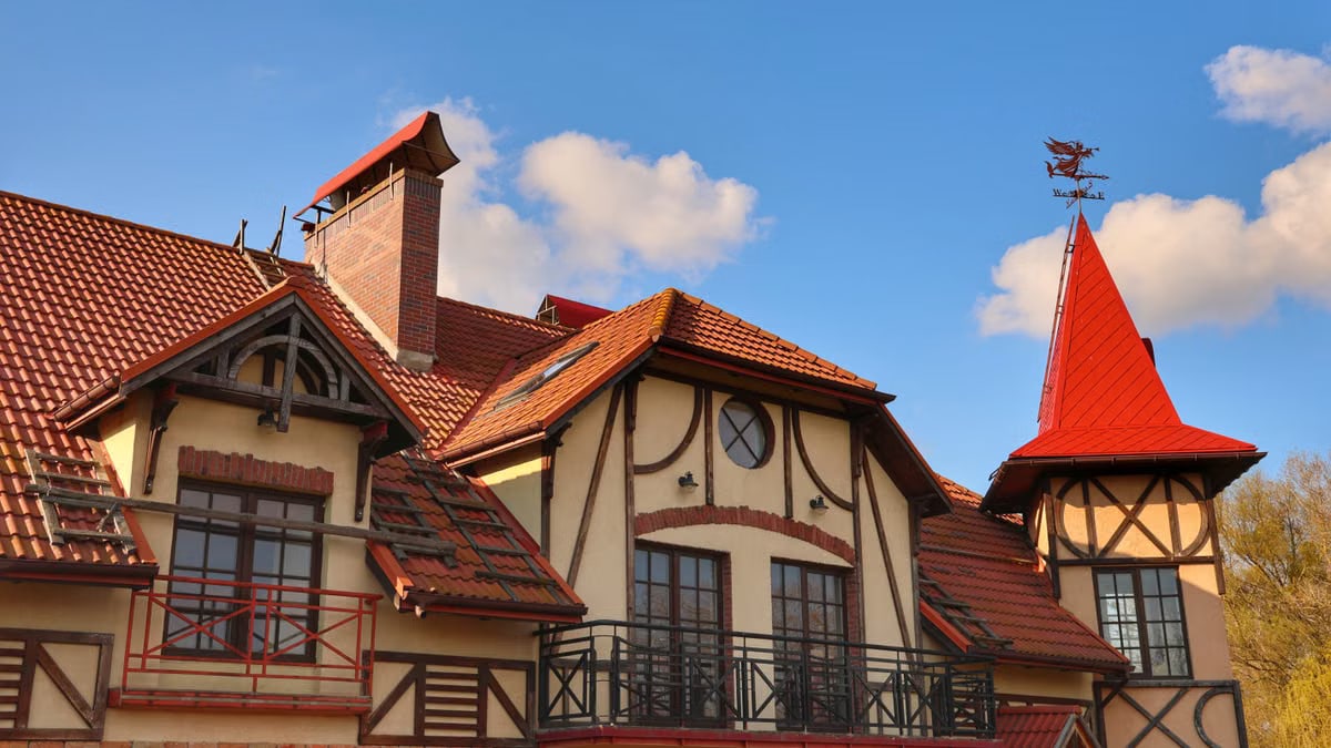 A beautiful European-style house with a distinctive red tiled roof against a clear blue sky.