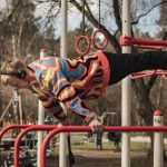 Young adult man exercises on outdoor gym bars in a colorful outfit in Vilnius, Lithuania.